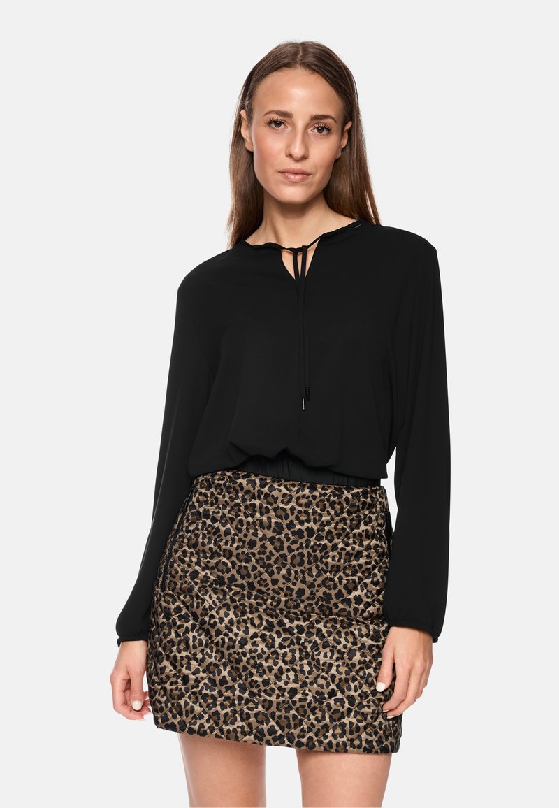 Schwarzes langärmliges Oberteil mit einem Schlüsselloch-Ausschnitt, kombiniert mit einem strukturierten Rock im braunen Leopardenmuster. Beide Kleidungsstücke weisen eine taillierte Passform auf.