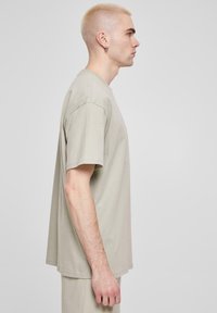 Lys beige crew-neck t-skjorte laget av bomull. Korte ermer, avslappet passform, jevn tekstur, synlige sømmer, brukt med matchende bukser.