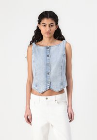 Himmelblaues Denim-Crop-Top mit Rundhalsausschnitt, sieben vertikalen Knöpfen und spitzem Saum. Wird über weißen hoch taillierten Hosen getragen.