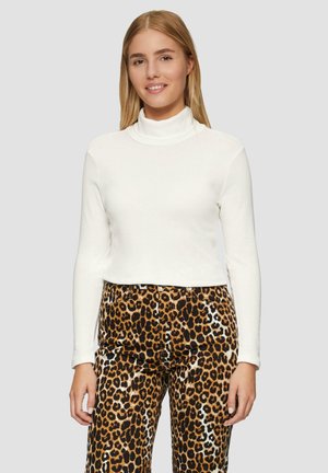 Witte langemouwen coltrui gecombineerd met hooggesneden broeken in bruin en zwart met luipaardprint; gladde textuur met een aansluitend ontwerp.