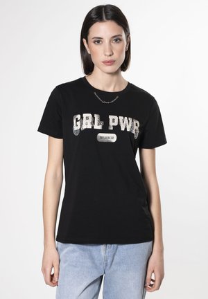 Camiseta de algodón negra con un gráfico de lentejuelas plateadas "GRL PWR" y etiqueta de "INFLUENCER", complementada con un diseño clásico de cuello redondo.