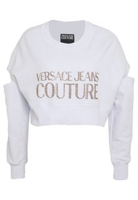 Vit kort sweatshirt med rund halsringning och sänkta axlar. Utsmyckad med "VERSACE JEANS COUTURE" i guldfärgade nitar.