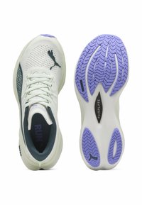 Witte textiel hardloopschoenen met een bovenwerk van mesh, een zwart Puma-logo en een paarse rubberen buitenzool met een gestippeld loopvlak.