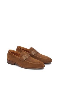 Brown suede loafers with mesh accents and brown leather strap. Rounded toe and flat sole design. Smooth texture with subtle stitching.