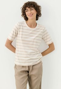 Lightweight, short-sleeve t-shirt in cream with varying beige horizontal stripes. Rounded neckline, soft texture, and relaxed fit.