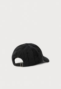 Casquette de baseball en denim noir vue de l'arrière avec une sangle ajustable et une boucle métallique sur un fond clair.