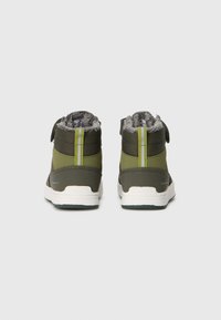 Botas impermeáveis verdes com um cabedal texturizado, forro de pêlo cinza e uma faixa amarela em contraste. Apresentam uma sola de borracha branca e uma fita de velcro.