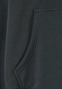 Tissu gris foncé en gros plan montrant une poche avec couture courbée et double surpiqûre sur un matériau doux et épais.