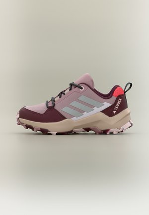 Buty do biegania po szlakach w kolorach różowym, bordowym i beżowym, z czarnymi sznurówkami, wytrzymałą podeszwą i logo Terrex na pięcie.