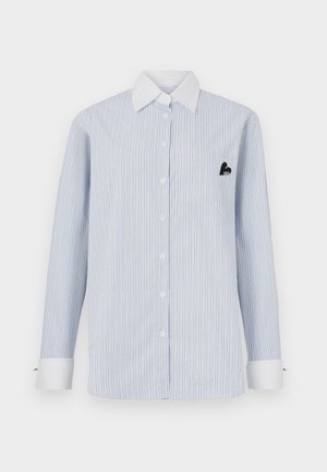 Camicia a maniche lunghe a righe di color azzurro chiaro con righe bianche. Presenta un colletto bianco, bottoni anteriori e una tasca con dettaglio logo nero.