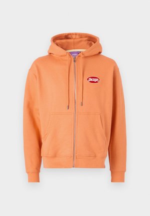 Orange zip-up hoodie made of soft fabric, featuring a front pocket, drawstring hood, and a red logo patch on the upper left side.