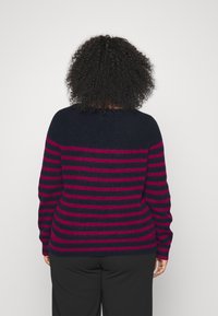 Stribet sweater i navyblå og magenta farver, blød tekstur, rundt halsudskæring og lange ærmer med en tætsiddende silhuet.