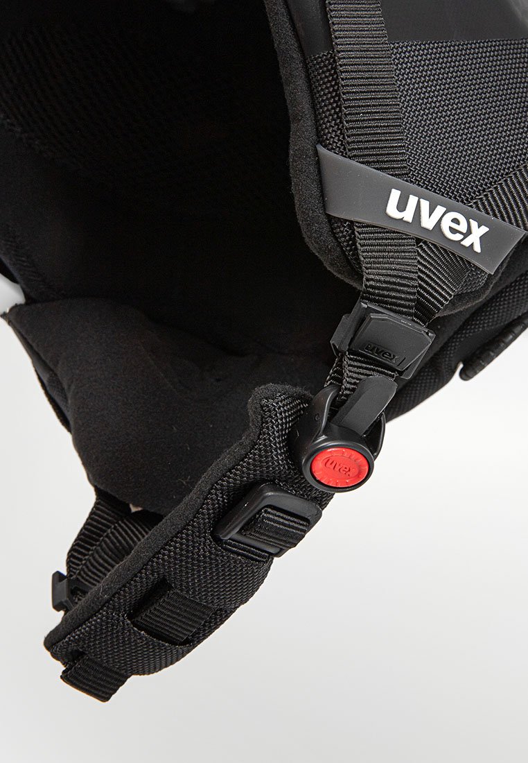 Schwarzer Helm mit gepolstertem Innenraum, verstellbaren Riemen und einem roten Schnellverschluss. Verfügt über strukturierten Stoff und Logodetails.