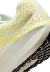 Scarpa da ginnastica in rete gialla con suola bianca spessa e battistrada nero, vista dal basso che mostra il tallone e parte del midsole.