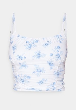 Fehér szövet felső kék virágmintával, vékony pántokkal, ráncolt textúrával és testhezálló szabással.