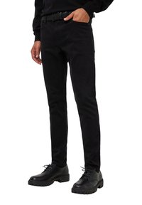 Jeans neri slim-fit realizzati in tessuto misto cotone, con un classico design a cinque tasche e indossati con scarpe nere stringate.