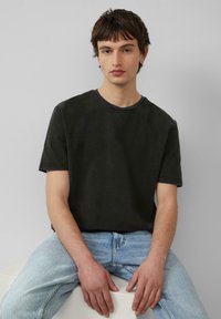 Dunkelgraues kurzärmeliges T-Shirt mit Rundhalsausschnitt, kombiniert mit hellblauen Jeans. Weiche Textur, minimalistisches Design.