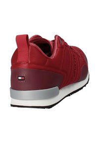 Scarpa sportiva rossa con tomaia testurizzata, collo imbottito, suola grigia e logo sulla parte posteriore. Design leggero e aerodinamico.