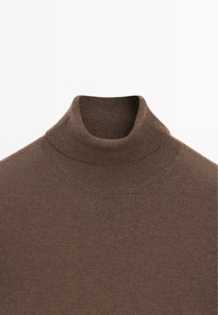 Maglione a collo alto marrone con texture a costine, caratterizzato da un collo alto e un design liscio e aderente.