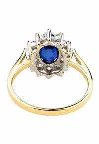 Anello in oro e argento con una pietra preziosa blu sfaccettata, circondata da piccole pietre trasparenti in un'impostazione dettagliata simile a artigli.