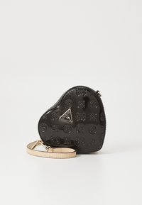 Svart hjerteformet håndveske laget av glanset materiale, med pregete mønstre, gullfarget beslag og en avtakbar lys tan-rem.