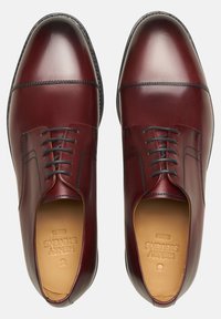 Bordeaux leren dresschoenen met een gepolijste afwerking, ronde neus, contrasterende zwarte stiksels en vijf paar oogjes voor veters.