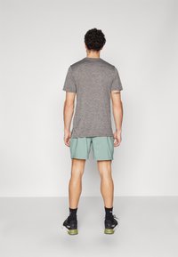 Gray short-sleeve t-shirt, light green shorts, black sneakers. T-shirt has a round neck and relaxed fit; shorts are knee-length.
