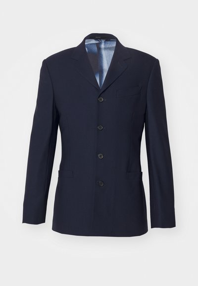 Blazer marine en tissu lisse avec un design structuré. Présente un revers cranté, six boutons, une poche frontale et deux poches latérales.