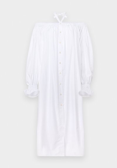 Bijela haljina s otkrivenim ramenima i napuhanim rukavima. Ima dugmad sprijeda i elastične manžete. Izrađena je od lagane tkanine s glatkom teksturom.