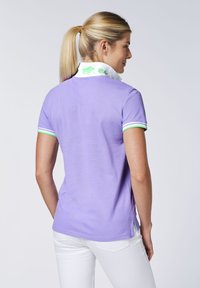 Lila Poloshirt aus Baumwolle mit kurzen Ärmeln, das grün-weiße gestreifte Akzente am Kragen und den Ärmeln aufweist sowie ein gebrandetes Kragen-Detail.