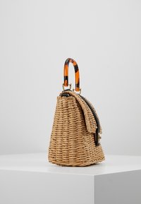 Borsa a mano in paglia intrecciata, di colore nocciola, forma curvata, manico in tartaruga e dettagli con zip nera. Presenta un lato con pattina per la chiusura.