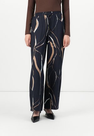 Marine bukser med et abstrakt beige og hvidt mønster, lavet af et blødt stof, med elastisk talje og vidde ben.