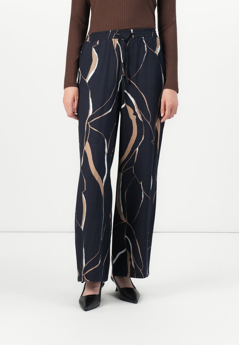 Pantalon bleu marine avec un motif abstrait beige et blanc, en tissu doux, présentant une taille élastique et une coupe ample.