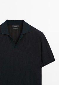 Polo shirt nera a maniche corte con texture a costine, scollo a V e colletto a tinta unita. Presenta strisce verticali all'interno del colletto. Etichetta del marchio visibile.