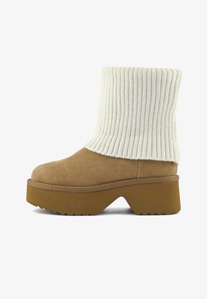 Tan suède platform enkellaars met dikke bruine zool en brede opgevouwen witte ribgebreide manchetten.