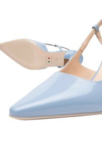Scarpe con tacco a punta in vernice blu chiaro con cinturino. Presentano una suola beige con texture stampata e branding all'interno.