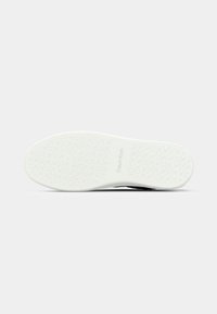 Sole delle sneakers Calvin Klein in gomma bianca testurizzata con motivi circolari e dettagli del logo. Design minimalista, forma piatta.