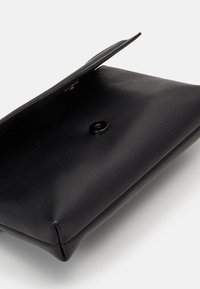 Pochette en cuir noir avec une finition texturée, de forme rectangulaire, et une fermeture à pression. Vue intérieure montrant l'intérieur et le rabat ouvert.