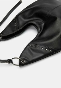 Fekete bőr táska ívelt dizájnnal, texturált felülettel, fémszegecsekkel a szélén, valamint levehető pánttal, kör alakú fém részlettel.