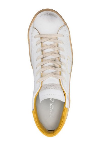 Sneaker di pelle bianca con lacci beige, dettagli gialli sul tallone e all'interno, e suola in gomma texturizzata. Leggeri segni di usura sulla punta.