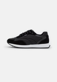 Sneaker neri in suede e pelle, caratterizzati da un design elegante, punta tonda, suola imbottita e chiusura con lacci. Dettaglio del logo "HUGO" visibile.