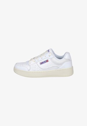 Zapatilla blanca con diseño perforado y logo morado. Presenta un cierre de cordones en el frente, un collar acolchado y suela de goma texturizada para un mejor agarre.