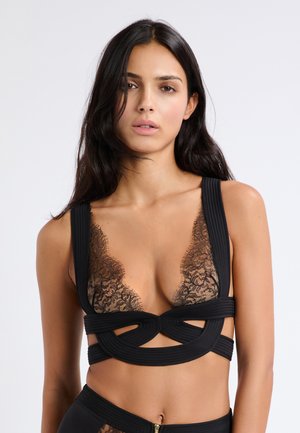 Reggiseno in pizzo nero con ampie spalline testurizzate, scollatura profonda, dettagli in pizzo intricati e design a taglio al centro.