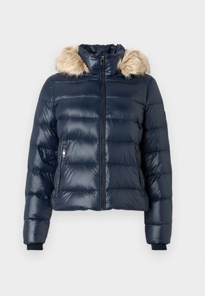 Navy blue quilted puffer jacket with front zipper, zippered side pockets, ribbed cuffs, and a detachable hood with beige faux fur trim.