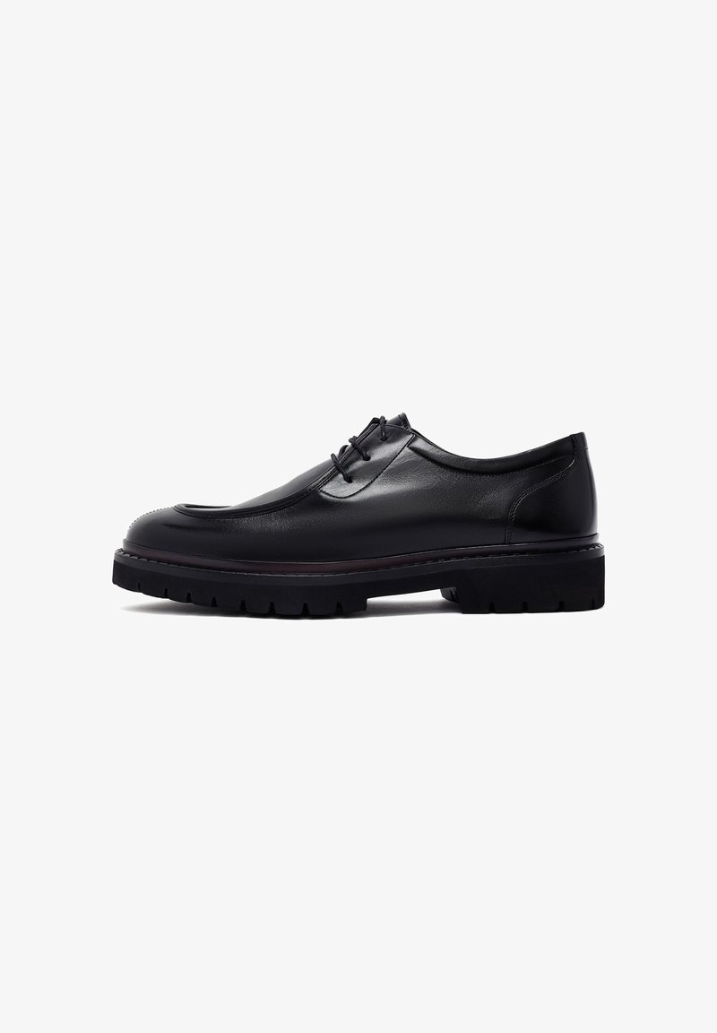 Zwarte leren schoen met een ronde teen, vetersluiting aan de voorkant en een chunky zool. Glad textuur met subtiele stiksels en een dikke loopvlak.