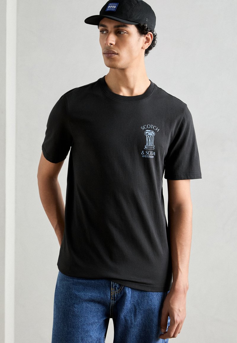 Black cotton t-shirt featuring a blue graphic print on the chest. Short sleeves and a crew neckline complement the casual design.