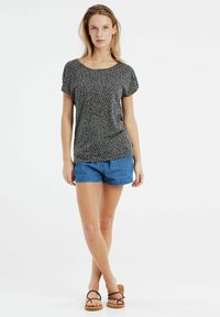 Top de manga corta con estampado de leopardo en negro y gris; combinado con pantalones cortos de mezclilla azules y sandalias marrones de tiras; textura de tejido suave.