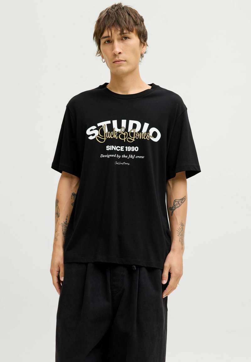 Czarny bawełniany t-shirt z graficznym wzorem z białym i złotym tekstem. Luźny krój z krótkimi rękawami i okrągłym dekoltem.