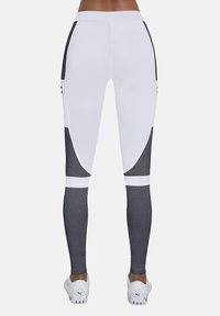 Białe legginsy sportowe z czarnymi panelami z siateczki po bokach, gładką teksturą i wysokim stanem. Zawierają geometryczne akcenty.