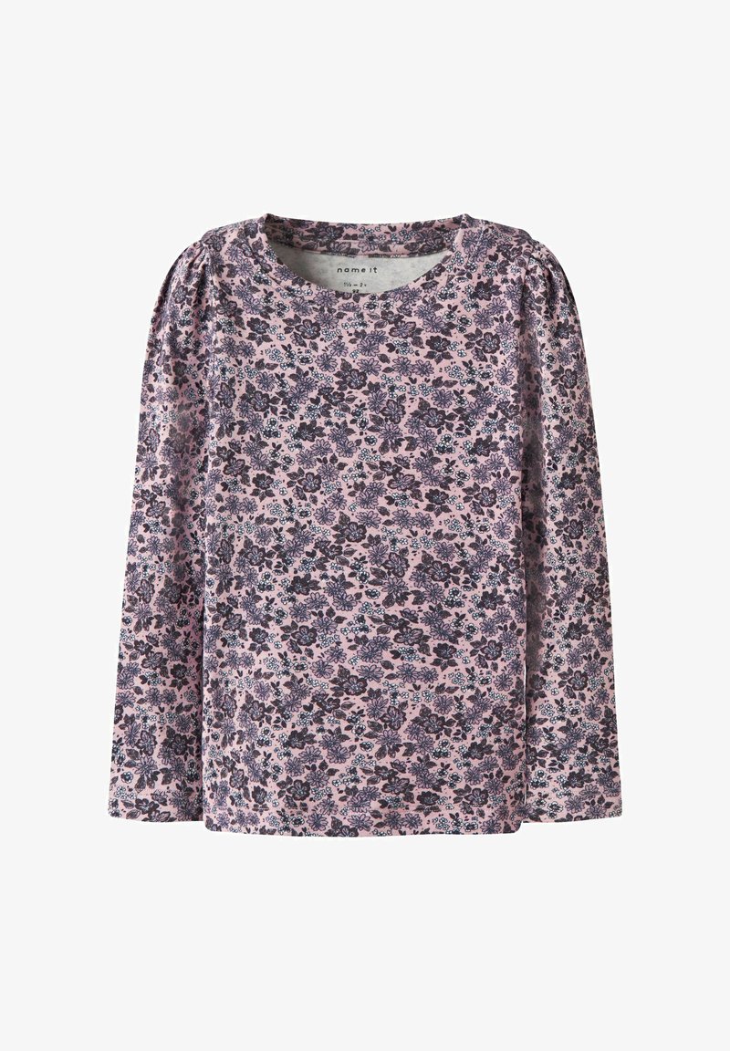 Blouse à manches longues en tissu rose avec un motif floral comportant des fleurs violettes foncées et bleues. Col rond avec des détails froncés sur les épaules.